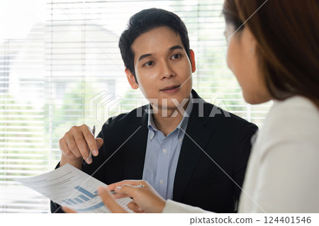 Client Consultation and Financial Discussion. A professional explaining financial data to a client in an office setting. 124401546