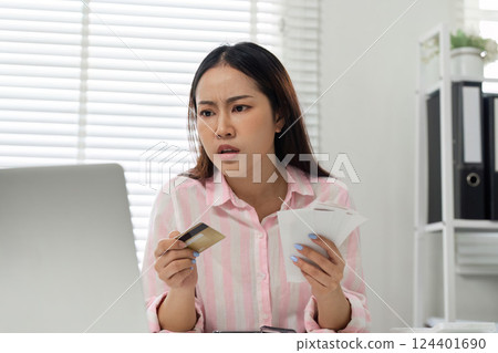 Finance and Decision Making. A woman appears concerned as she navigates her home office financial tasks. 124401690