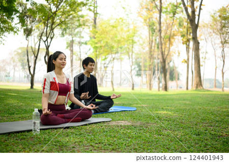 Man and woman practicing meditation together in a park. Mindfulness and mental health concept Man and woman practicing meditation together in a park. Mindfulness and mental health concept 124401943