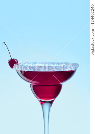 Cherry cocktail in elegant glass with sweet and sour rim against bright blue background. Concept of vacation, cocktails Cherry cocktail in elegant glass with sweet and sour rim against bright blue background. Concept of vacation, cocktails 124402240