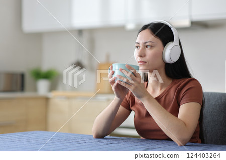 Distracted asian woman drinking and listening audio 124403264