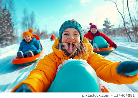 A group of children sledding down a hill in the snow 124404891