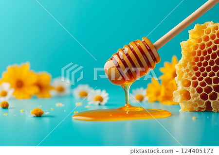 A honey dipper with honey dripping from it next to a honeycomb 124405172
