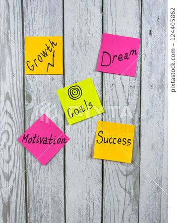 Colorful sticky notes with motivational words such as Growth, Dream, Goals, Motivation, and Success pinned on white wooden background. Ideal for illustrating motivation, planning, and goal concept 124405862