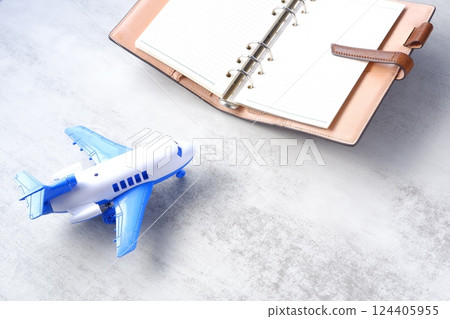 Image of an airplane and an open ring organizer planning your next long vacation trip 124405955