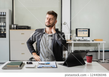 Male businessman is doing a stretchy posture due to sitting in the office for too long, office syndrome concept. Male businessman is doing a stretchy posture due to sitting in the office for too long, office syndrome concept. 124406046
