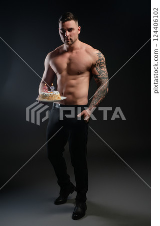 Celebrating a special birthday with a fit man holding a cake and candles 124406102