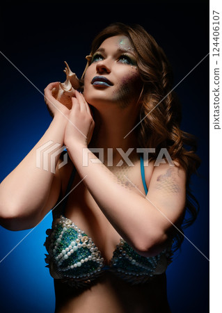 Woman embodies mermaid through body art and cosplay in studio setting Woman embodies mermaid through body art and cosplay in studio setting 124406107