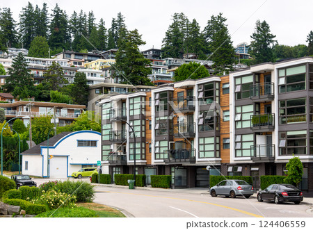 A perfect neighborhood. Uphill residential area with cars parked on the streets around the building 124406559