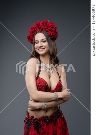 Woman in red costume with flower crown poses elegantly for photo shoot Woman in red costume with flower crown poses elegantly for photo shoot 124406978