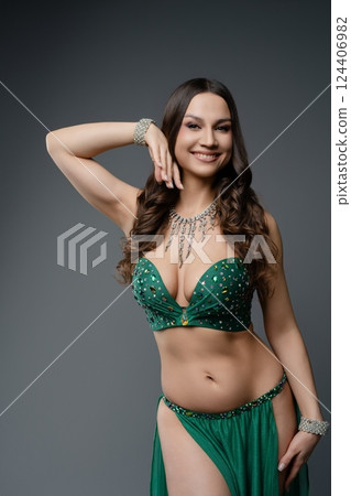 Elegant belly dancer poses gracefully in a shimmering green outfit Elegant belly dancer poses gracefully in a shimmering green outfit 124406982