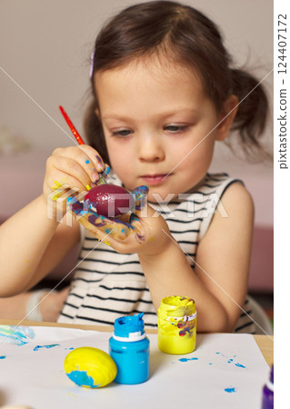 Little child girl paint Easter eggs at home. kid is preparing for Easter. 124407172