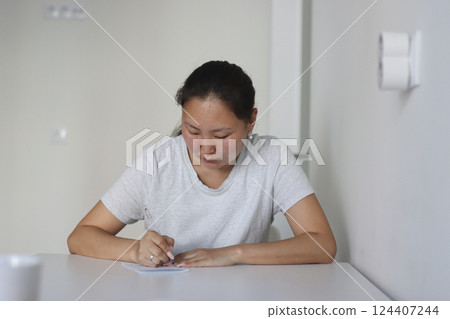 Asian woman writing at home filling out form 124407244