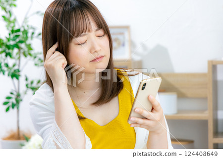 一位年輕女子一臉憂慮地看著她的智慧型手機 124408649