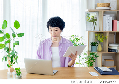 A middle-aged woman teleworking in the living room A middle-aged woman teleworking in the living room 124408672