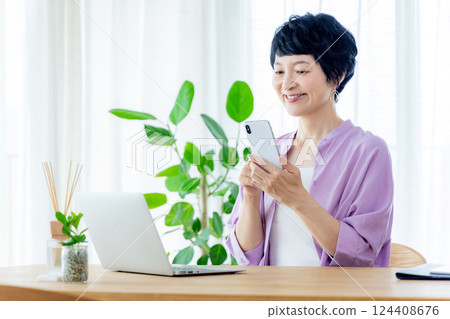 Middle-aged woman operating a smartphone Middle-aged woman operating a smartphone 124408676