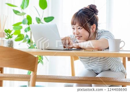 使用一台電腦在客廳裡的年輕女子 124408690