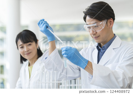 Men and women in white coats conducting experiments Men and women in white coats conducting experiments 124408972