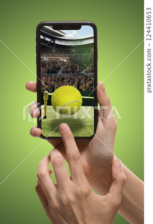 Person using smartphone to access tennis sports app, translation of live match updates. Tennis ball and court with filled stands. 124410653