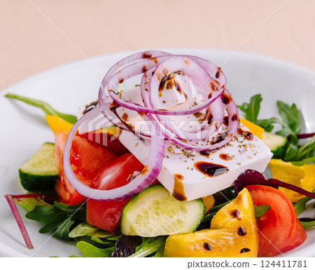 Fresh greek salad with feta cheese and vegetables on a white plate Fresh greek salad with feta cheese and vegetables on a white plate 124411781