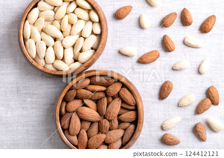 Almonds, with seed coats and blanched, in wooden bowls, on linen fabric. Fruits of Prunus amygdalus, syn. Prunus dulcis, ready-to-eat as snack or as ingredient for baking. Close up from above. Photo Almonds, with seed coats and blanched, in wooden bowls, on linen fabric. Fruits of Prunus amygdalus, syn. Prunus dulcis, ready-to-eat as snack or as ingredient for baking. Close up from above. Photo 124412121