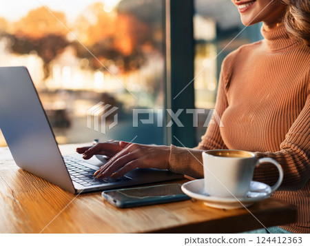 Hands of a woman operating a laptop in a cafe 124412363