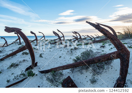 Rusty old anchors on the beach at the Anchor Cemetary graveyard at Praia do Barril beach in Tavira, Algarve, Portugal 124412592