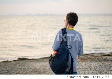 Back view of a man walking on the beach 124412944