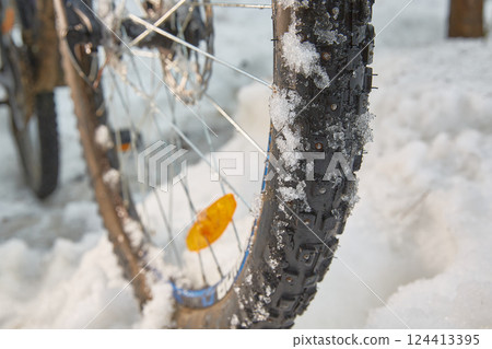 Winter cycling. Close-up of a wheel in the snow. 124413395