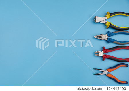 Pliers of different types with a copy space on a blue background. top view Pliers of different types with a copy space on a blue background. top view 124413400