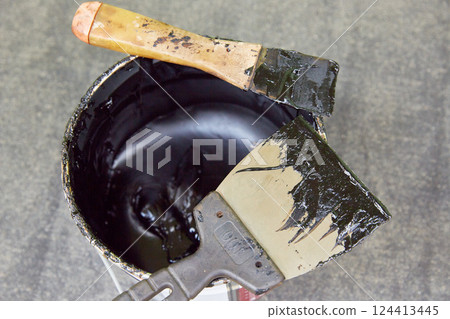 Black mastic in a jar with spatulas. Waterproofing. Waterproofing insulation of a roof. 124413445