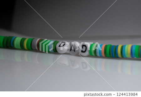 Green Bracelet Displaying Word "Dad" on Glossy Surface with Reflection 124413984
