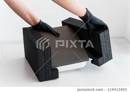 Hands in gloves carefully unpacking protective foam packaging from electronic equipment Hands in gloves carefully unpacking protective foam packaging from electronic equipment 124413993
