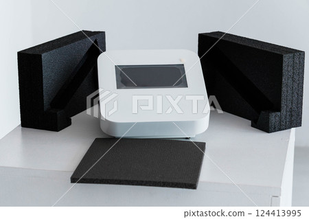 Modern Tech Device with Protective Black Foam Packaging on White Table 124413995