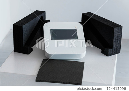Modern White Electronic Device Displayed With Black Protective Foam Packaging on Minimalistic Platform Modern White Electronic Device Displayed With Black Protective Foam Packaging on Minimalistic Platform 124413996