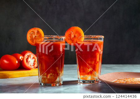 Two Bloody Mary cocktails in glass served with tomato slice and salt on dark background. Red cocktail. Alternative taste. Dirty dump drink Two Bloody Mary cocktails in glass served with tomato slice and salt on dark background. Red cocktail. Alternative taste. Dirty dump drink 124414436