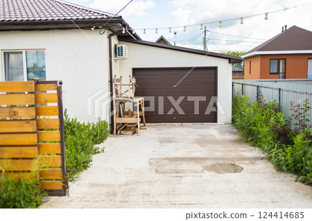 Wooden fence near white house and driveway. Functional exterior maintenance, emphasizes on organized management Wooden fence near white house and driveway. Functional exterior maintenance, emphasizes on organized management 124414685