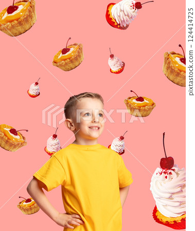 Smiling boy in yellow shirt surrounded by cherry cupcakes and mini tarts on pink background. Smiling boy in yellow shirt surrounded by cherry cupcakes and mini tarts on pink background. 124414725