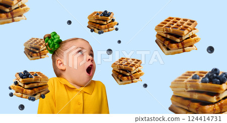 Excited girl, child in yellow shirt with green bun staring up at floating waffles and blueberries on light blue background. Excited girl, child in yellow shirt with green bun staring up at floating waffles and blueberries on light blue background. 124414731