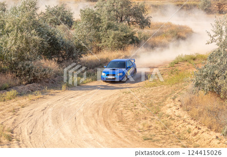 Blue Rally Car on a Winding Dirt Road 124415026