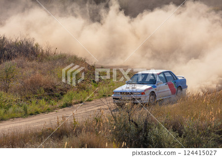 Large Cloud of Dust and Rally Car on a Dirt Corner 124415027