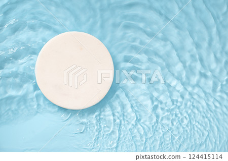 Marble white podium for cosmetics in blue water with splashes and waves. Space for design. product placement. Copy space. Top view 124415114