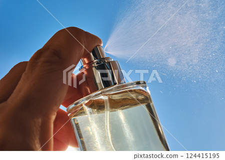 Spraying perfume against the sky. 124415195