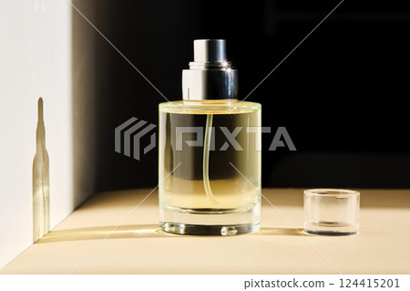 Perfume on a beige background in the rays of bright sun with beautiful highlights. 124415201