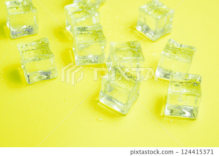 Ice cubes with water drops scattered on a lemon yellow background, top view. 124415371