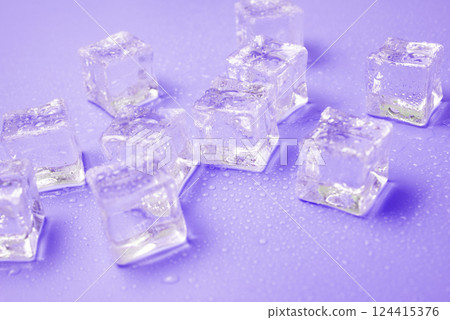 Ice cubes with water drops scattered on a violet background, top view. 124415376