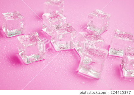 Ice cubes with water drops scattered on a pink background, top view. 124415377