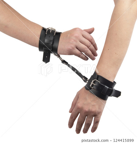 Toy black leather handcuffs on hand isolated on the white background Toy black leather handcuffs on hand isolated on the white background 124415899