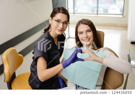 Doctor and patient are doing heart with hands in office. The doctor is grateful for the trust 124416850