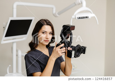 Woman dentist holding camera in hands and taking photos of patient teeth at modern clinic 124416857